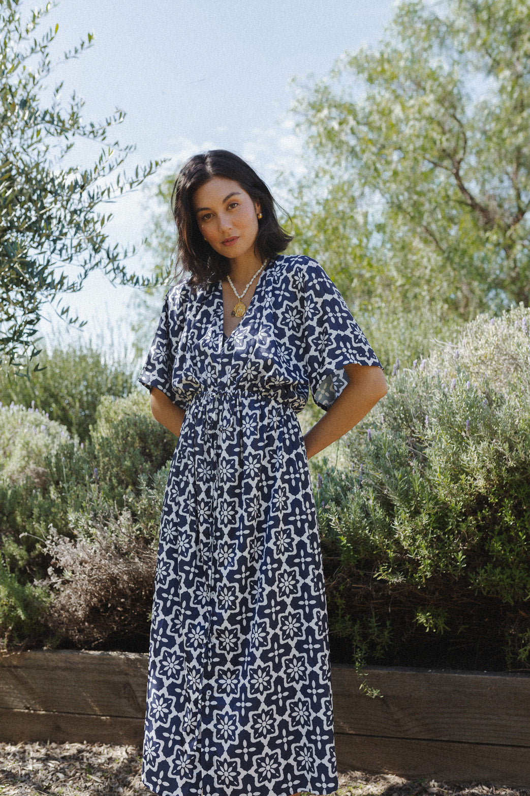 Woman wears long navy blue dress with white tile detailing.