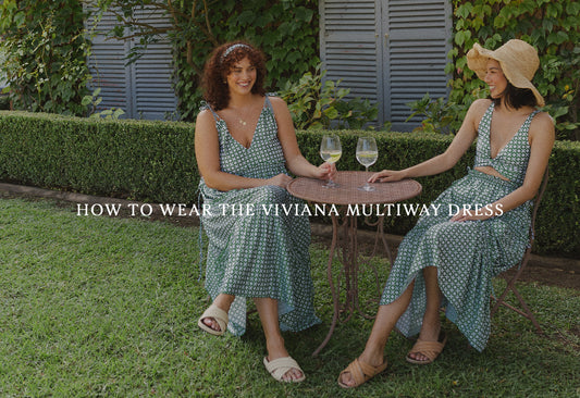 Two women wear green dresses, sitting at picnic table.