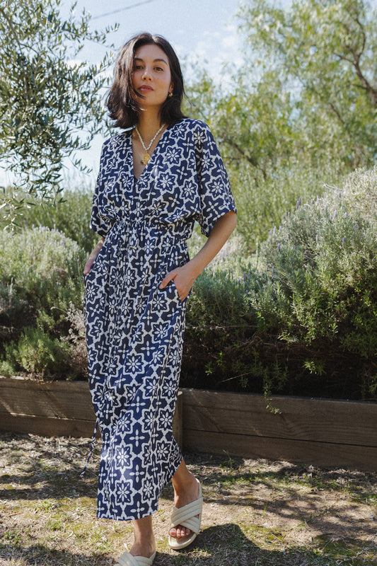 Woman wearing midnight navy maxi dress. Posing with hands in the dress pockets.