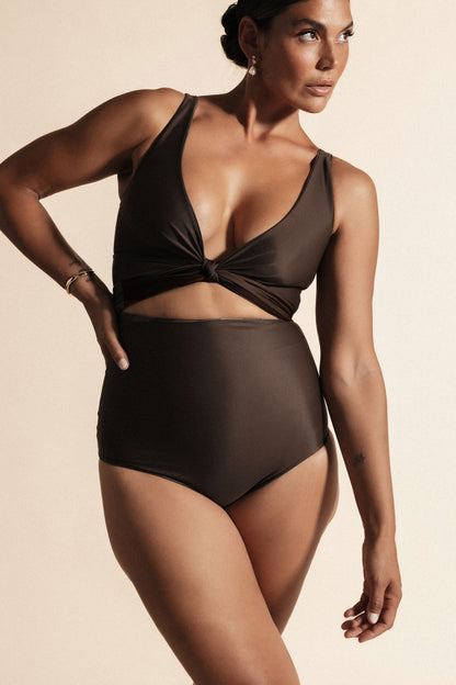 Woman stands with her hand on her hip wearing a solid brown, high waisted bikini set. The top is cinched at the bust with a matching tie.