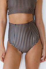 Woman wears high neck striped bikini and high waisted bottoms.
