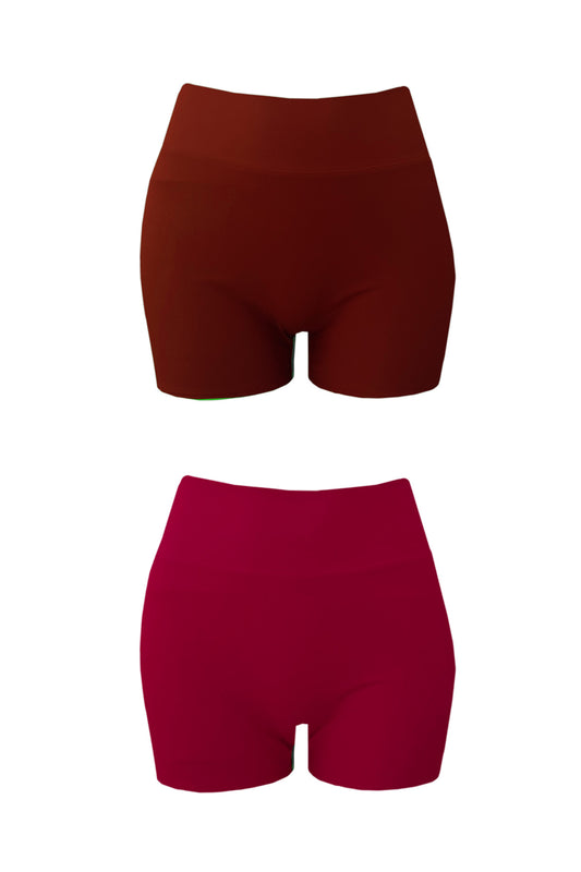 Woman stands on a beach wearing a raspberry coloured swim set featuring high waisted shorts and a two piece wrap bikini top.