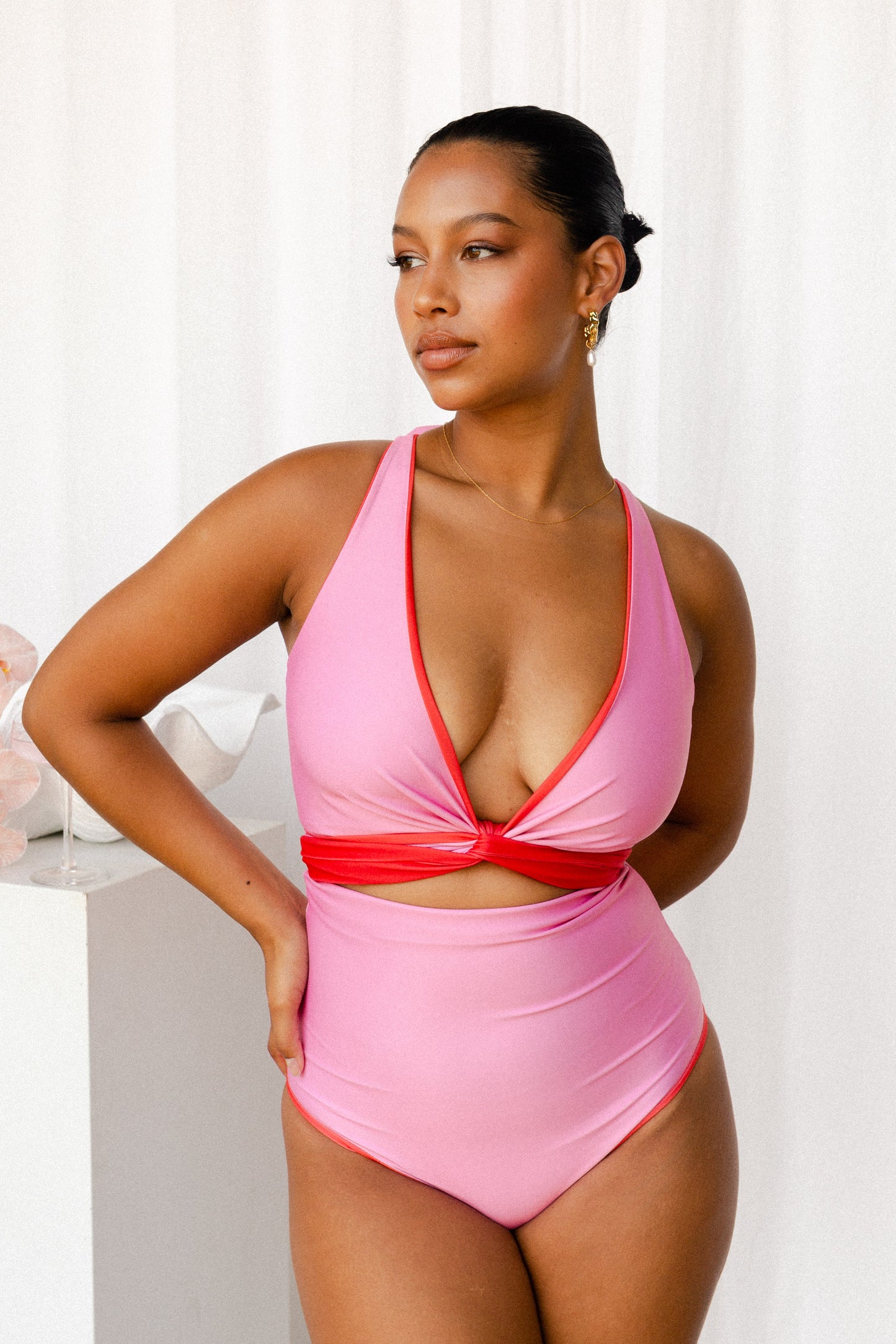 Woman wears a bikini set with a red tie used to cinch the bust and create a V-neck.