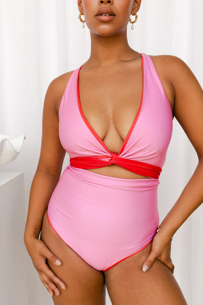 Pink bikini set with a red tie used to cinch the bust and create a V-neck.