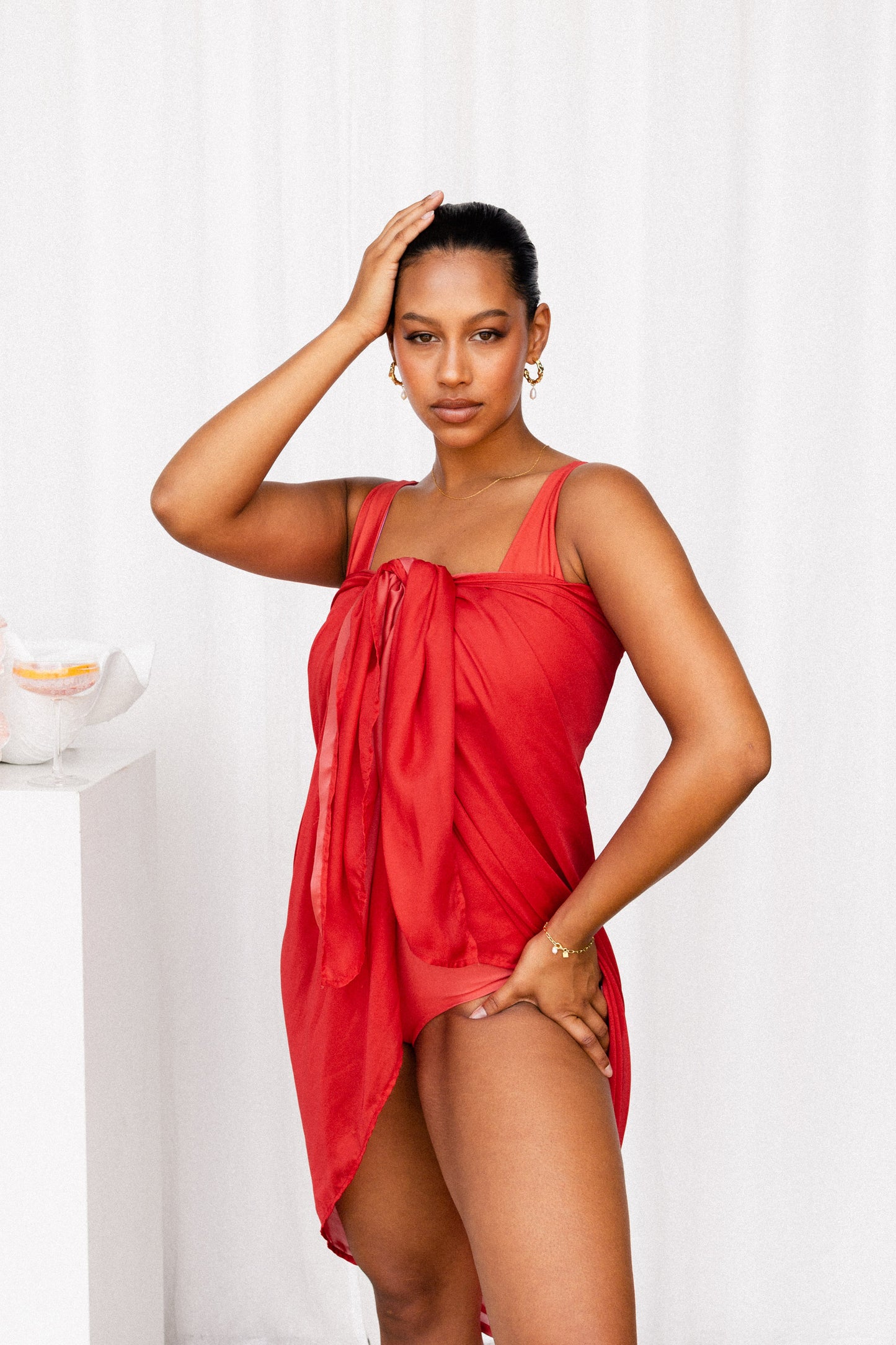 Woman wears a luxurious red sarong tied at the bust to create the illusion that she is wearing a cocktail dress.