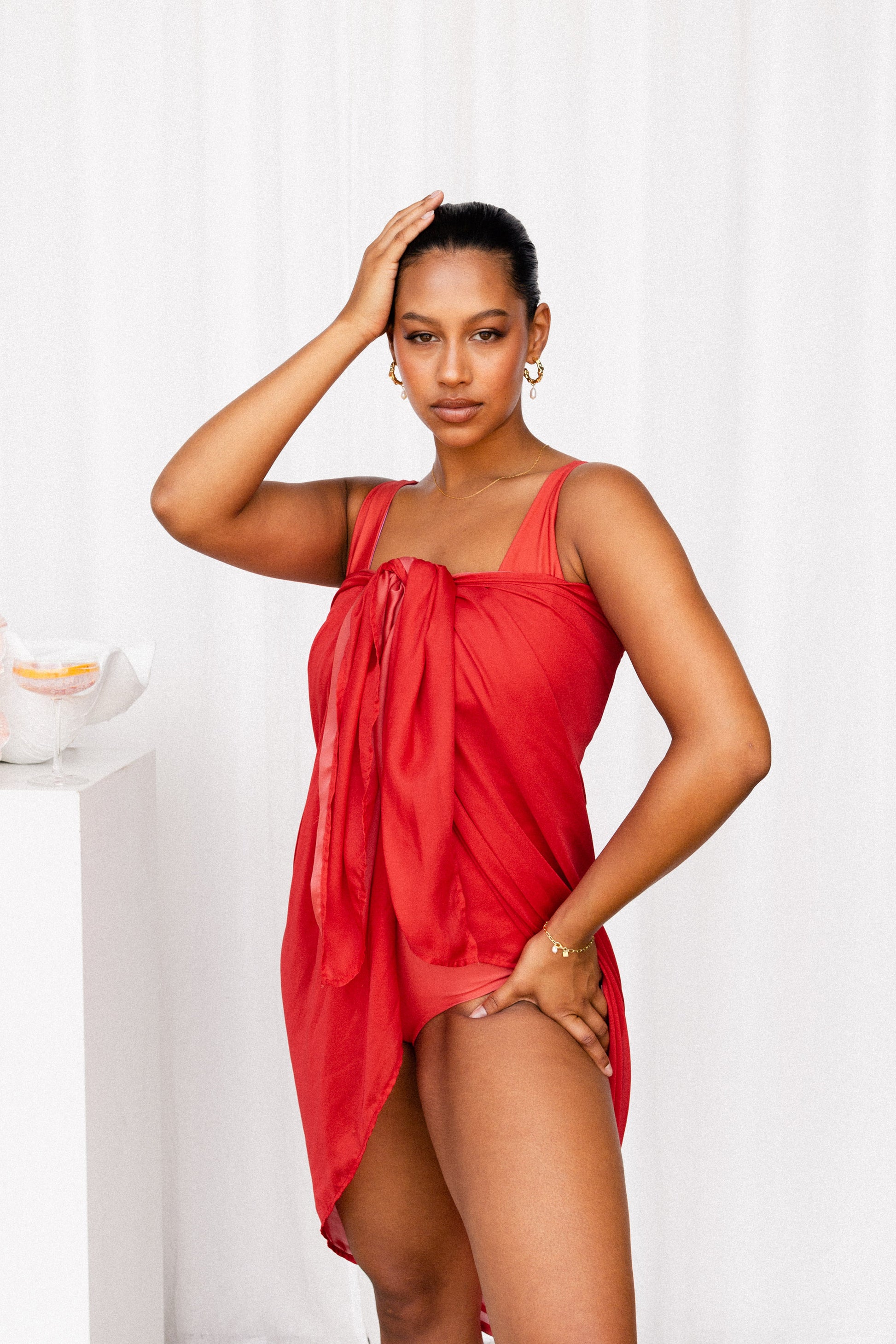 Woman wears a luxurious red sarong tied at the bust to create the illusion that she is wearing a cocktail dress.