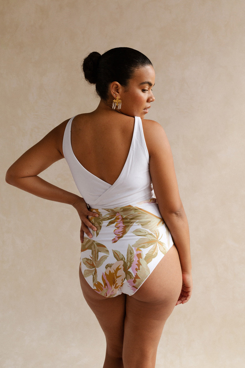A woman stands with her back facing the camera, showcasing the flattering bum coverage of the high waisted floral print Bahamas bikini bottoms.