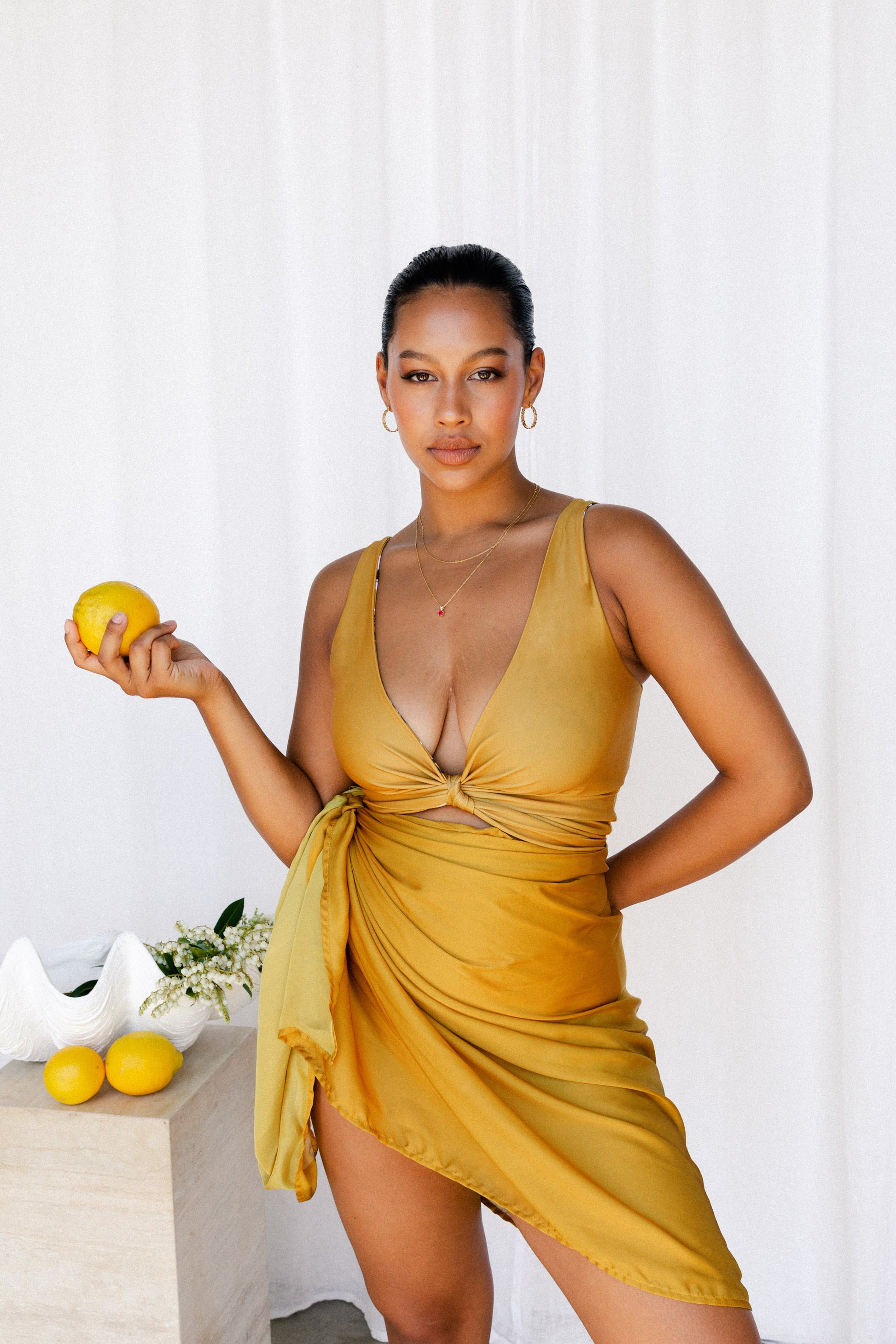 Woman wearing a beautiful mustard bikini set with matching sarong.