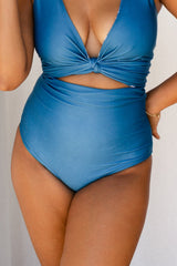 Woman wearing solid ocean blue bikini set holds a white star fish ornament.