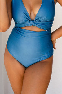 Woman wearing solid ocean blue bikini set holds a white star fish ornament.
