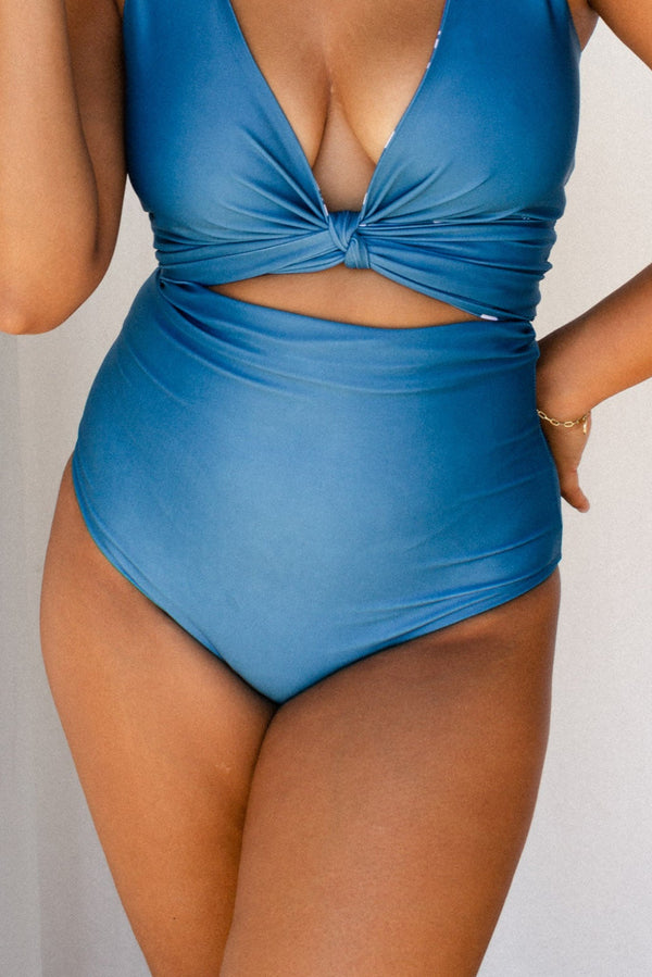 Woman wearing solid ocean blue bikini set holds a white star fish ornament.