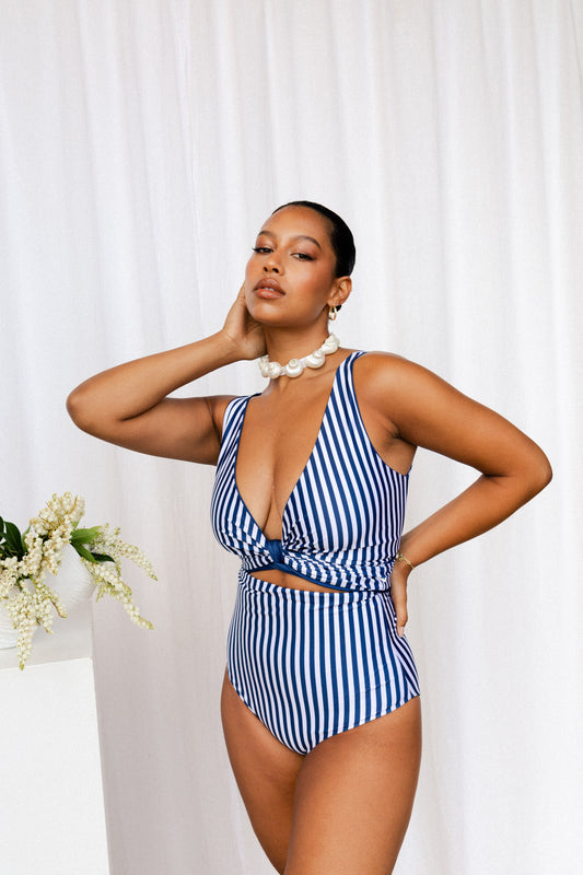 Woman wearing navy and white bikini set with vertical stripes. The bottoms are high waisted and top is cinched at the bust to create a plunging V neckline.