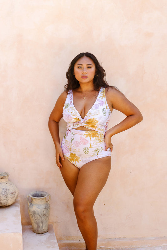 Woman posing in front of a beige stone wall dressed in the fully reversible Havana bikini 